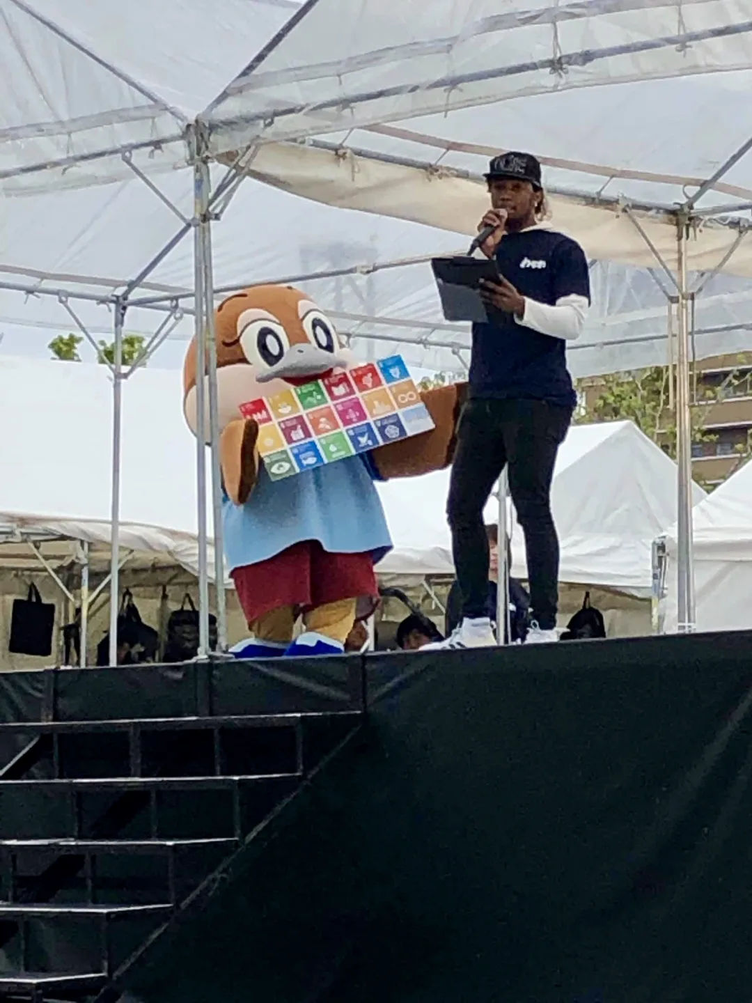 ステージでSDGsボードを掲げる大阪府公式キャラクター「もずやん」と出演者