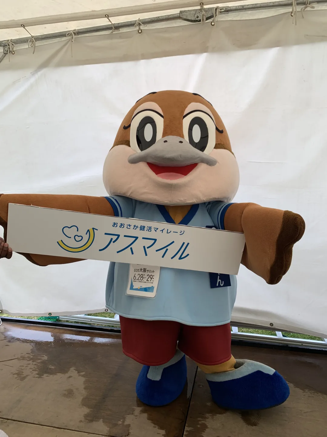 「おおさか健活マイレージ アスマイル」のボードを持つ「もずやん」